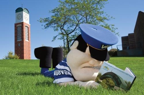 Louie the Laker lying on the grass near a clock tower